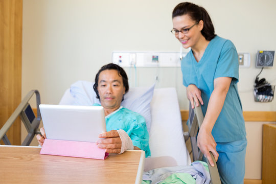 Nurse And Male Patient Looking At Digital Tablet