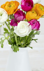 bouquet of white, pink and orange buttercups on wooden table