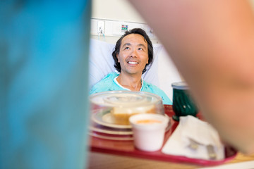 Happy Patient Looking At Nurse Serving Breakfast