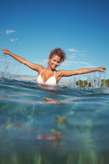 Happy young woman in sea with open hands.