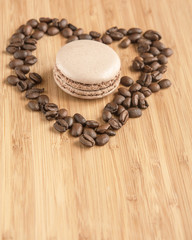Макарун в сердце из кофейных зерен на деревянном фоне