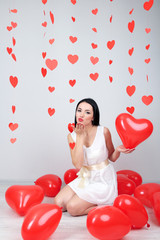 Attractive young woman with balloons in room on Valentine Day