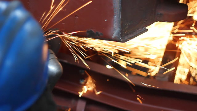 Worker grinding a metal construction with grinding wheel