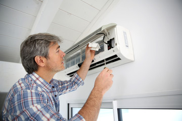 Repairman fixing air conditioner unit - obrazy, fototapety, plakaty