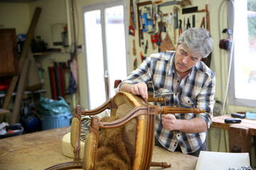 Craftsman repairing antique armchair in workshop