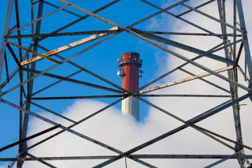 Chimneys in clouds of smoke by metal grid, pollution.