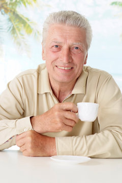 Old man drinking coffee at table