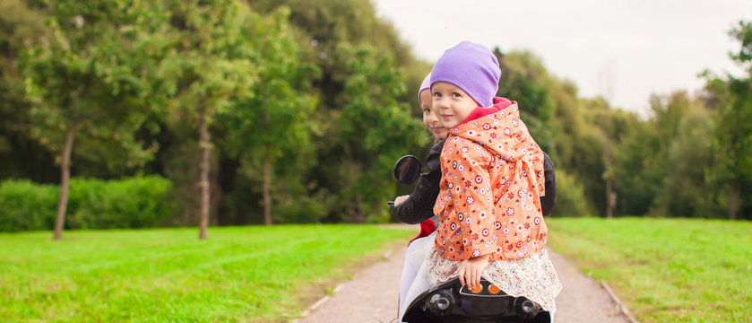Portrait of little cute girls ride a motorbike outdoors