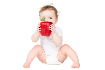 Funny baby biting on a big red paprika, isolated on white