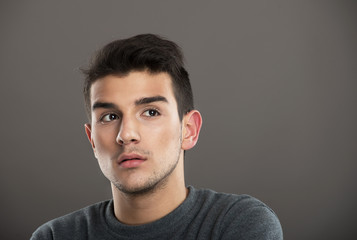 Studio portrait of a pensive youth on gray background