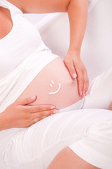 Fototapeta na wymiar Belly of pregnant woman with smile symbol on it