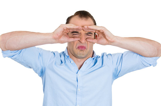 Funny displeased man looking through imaginary binoculars