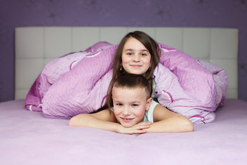 siblings having fun in bed before sleeping, two happy friends - 61329348