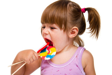 Cute little girl eating a colored lollipop