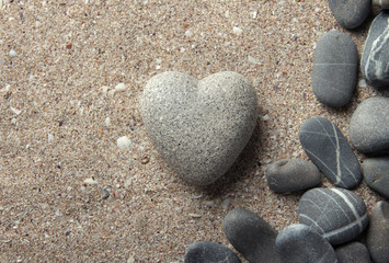 Fototapeta na wymiar Szary kamień w kształcie serca, na tle piasku