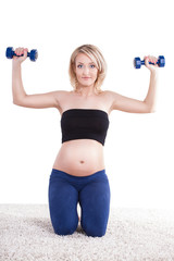 A pregnant woman exercising with a light weights - isolated
