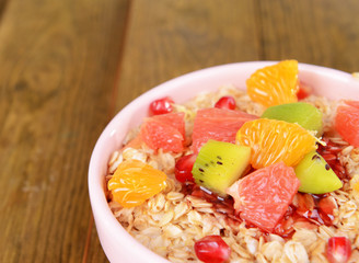 Delicious oatmeal with fruit in bowl on table close-up
