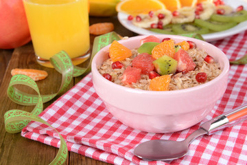 Delicious oatmeal with fruit in bowl on table close-up