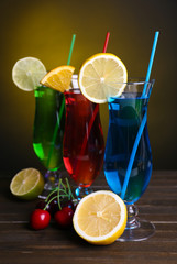 Glasses of cocktails on table on dark yellow background