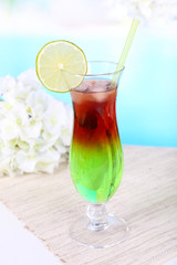 Glass of cocktail on table on light blue background