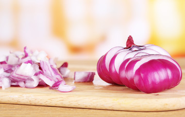 Cut onion on cutting board on wooden table, on bright