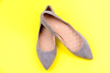 Beautiful grey female shoes, on yellow background