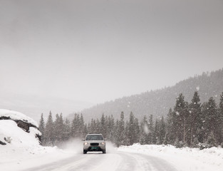 car driving along snow covered road in a snowstorm