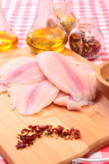 Obraz na płótnie Canvas Raw fish tilapia on cutting board and spices