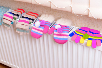 Knitted gloves drying on heating radiator