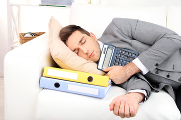 Elegant young businessman sleeping on sofa, at home