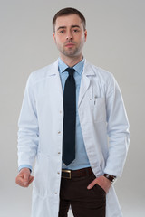 Serious mature male doctor standing on grey background