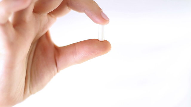 Hands showing a pill, close up