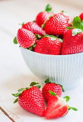 Closeup of strawberries in a bowl on wooden backgorund