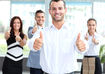attractive businessman with team in office showing thumbs up 