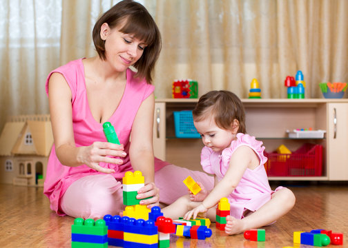 mother and her kid play with block toys at home interior