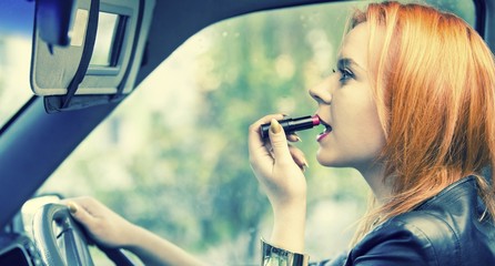 Woman applying lipstick on lips in car. Danger on road.