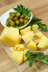 Parmesan cheese, fresh herbs and olives on wooden background