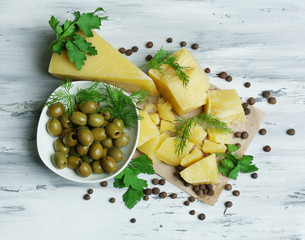 Parmesan cheese, fresh herbs and olives on wooden background