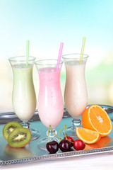 Milk shakes with fruits on table on light blue background