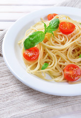 Delicious spaghetti with tomatoes on plate on table close-up