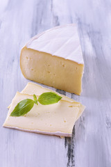 Tasty Camembert cheese with basil, on wooden table