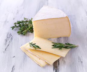 Tasty Camembert cheese with rosemary and thyme, on wooden table