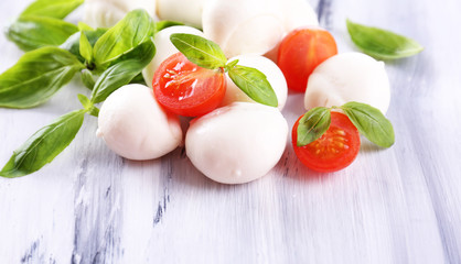Tasty mozzarella cheese with basil and tomatoes, on wooden