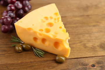 Piece of cheese with green olives, on wooden background