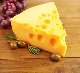 Piece of cheese with green olives, on wooden background