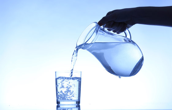 Pour Water From  Pitcher Into  Glass, On Dark Blue Background