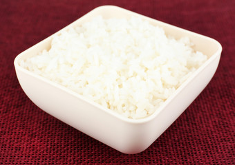 Cooked rice in bowl on red background