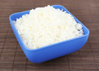 Cooked rice in bowl on bamboo background