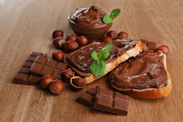 Bread with sweet chocolate hazelnut spread on wooden background