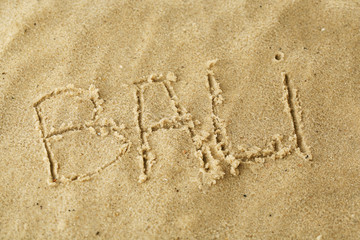 Inscription Bali on wet sand close-up background